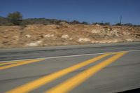 a photo taken from a vehicle window of the road going through a canyon and hillside