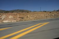 a photo taken from a vehicle window of the road going through a canyon and hillside