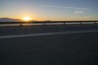 a photo taken of the sun on the road at sunrise time in front of mountains