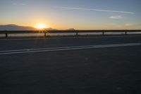 a photo taken of the sun on the road at sunrise time in front of mountains