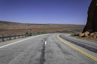 a paved mountain road in the middle of an arid area with mountains in the background