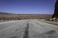 a paved mountain road in the middle of an arid area with mountains in the background