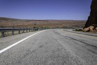 a paved mountain road in the middle of an arid area with mountains in the background