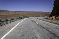 a paved mountain road in the middle of an arid area with mountains in the background