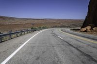 a paved mountain road in the middle of an arid area with mountains in the background