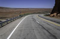 a paved mountain road in the middle of an arid area with mountains in the background