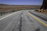 a paved mountain road in the middle of an arid area with mountains in the background