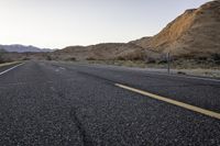 a wide open country road with an old speed sign on the side of it at sunset