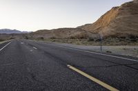 a wide open country road with an old speed sign on the side of it at sunset