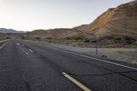 a wide open country road with an old speed sign on the side of it at sunset