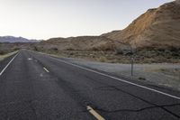 a wide open country road with an old speed sign on the side of it at sunset