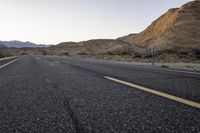 a lone road with no people on it in the desert area at dusk, looking out toward a mountainous landscape