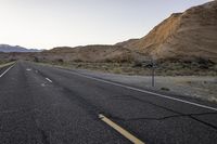 a lone road with no people on it in the desert area at dusk, looking out toward a mountainous landscape