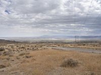 power lines stretching across the desert toward the horizon of the distant field and distant land