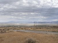 power lines stretching across the desert toward the horizon of the distant field and distant land