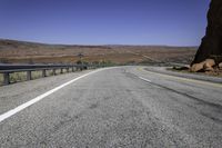 a long empty road with two lanes on both sides and a mountain in the distance