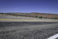 a very wide empty highway with mountains in the distance as seen from a street corner