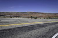 a very wide empty highway with mountains in the distance as seen from a street corner