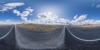 an empty road with clouds in the sky as seen from a low perspective point perspective lens