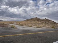 the road is winding through the landscape towards a mountain range and empty parking space for cars