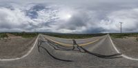 two winding roads on the side of the road with grass and trees behind them and a dark storm cloud in the distance