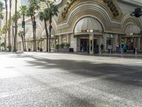 the entrance to a mall with people walking around and shops lined up, on the sidewalk