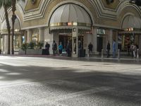 the entrance to a mall with people walking around and shops lined up, on the sidewalk