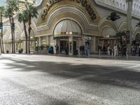 the entrance to a mall with people walking around and shops lined up, on the sidewalk