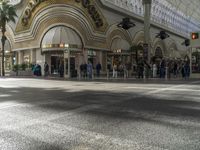 the entrance to a mall with people walking around and shops lined up, on the sidewalk