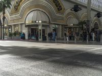 the entrance to a mall with people walking around and shops lined up, on the sidewalk