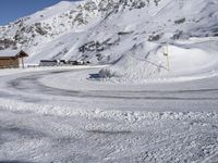 a snowy road with a snow covered mountain in the background with tracks running along it