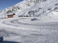 a snowy road with a snow covered mountain in the background with tracks running along it