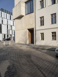 a person with a suitcase walking across an outside courtyard in front of a building,