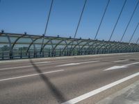 a truck driving across a bridge near a street corner near buildings and a bridge with many cables