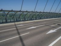 a truck driving across a bridge near a street corner near buildings and a bridge with many cables