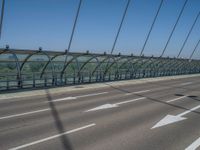 a truck driving across a bridge near a street corner near buildings and a bridge with many cables