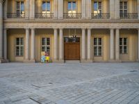 a courtyard with a building on the other side and a large white building with many windows