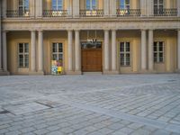 a courtyard with a building on the other side and a large white building with many windows