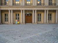 a courtyard with a building on the other side and a large white building with many windows