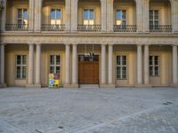 a courtyard with a building on the other side and a large white building with many windows