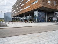 the entrance to a modern building with lots of windows and a brick driveway outside the building