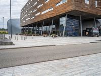 the entrance to a modern building with lots of windows and a brick driveway outside the building