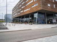 the entrance to a modern building with lots of windows and a brick driveway outside the building