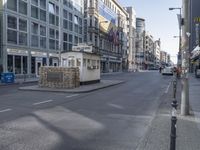 this small booth is next to a street and several buildings are on either side the intersection