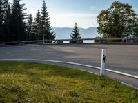 a curved road leading through the woods to mountains in the background with a car driving down it