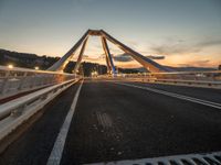 the sun sets over the roadway with an overhead view of a bridge and car's reflection