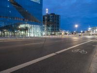 a bike lane that has some buildings on the side of it at night with lights on and traffic on