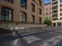 a brick courtyard has steps leading up to it, and a blue umbrella is on the ground