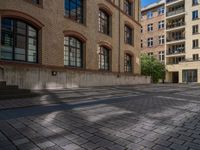 a brick courtyard has steps leading up to it, and a blue umbrella is on the ground