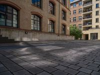 a brick courtyard has steps leading up to it, and a blue umbrella is on the ground